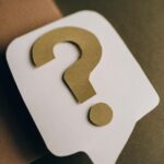 Artistic paper craft of a question mark symbol on a textured green surface.