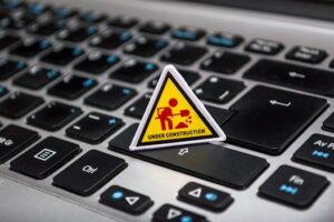 A miniature under construction sign placed on a laptop keyboard symbolizing digital development.